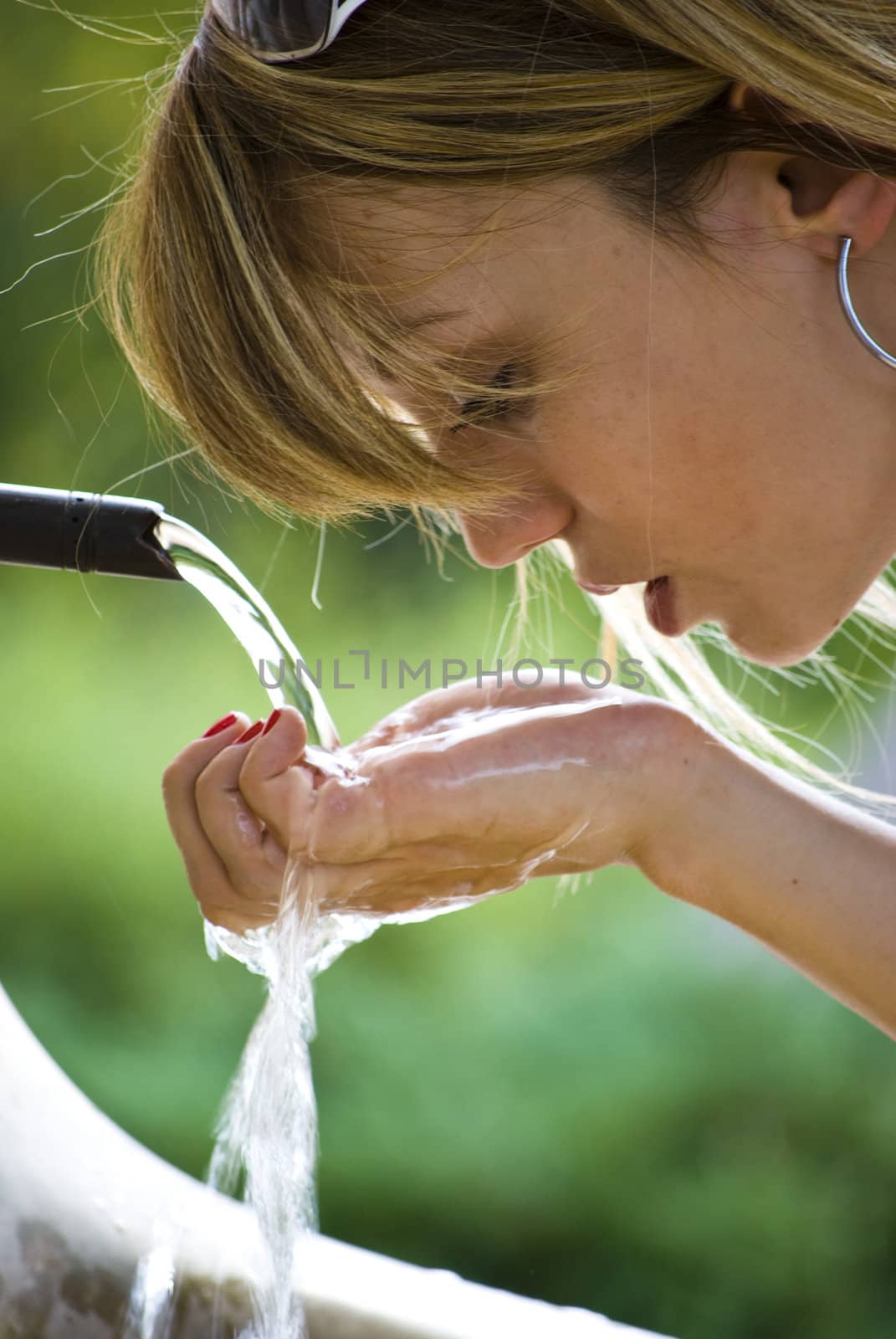 young beautiful woman drinking water in park