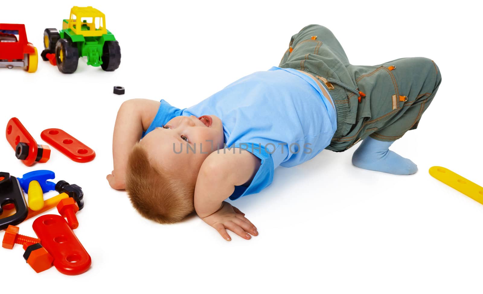 A little boy fooling around on the floor among the toys