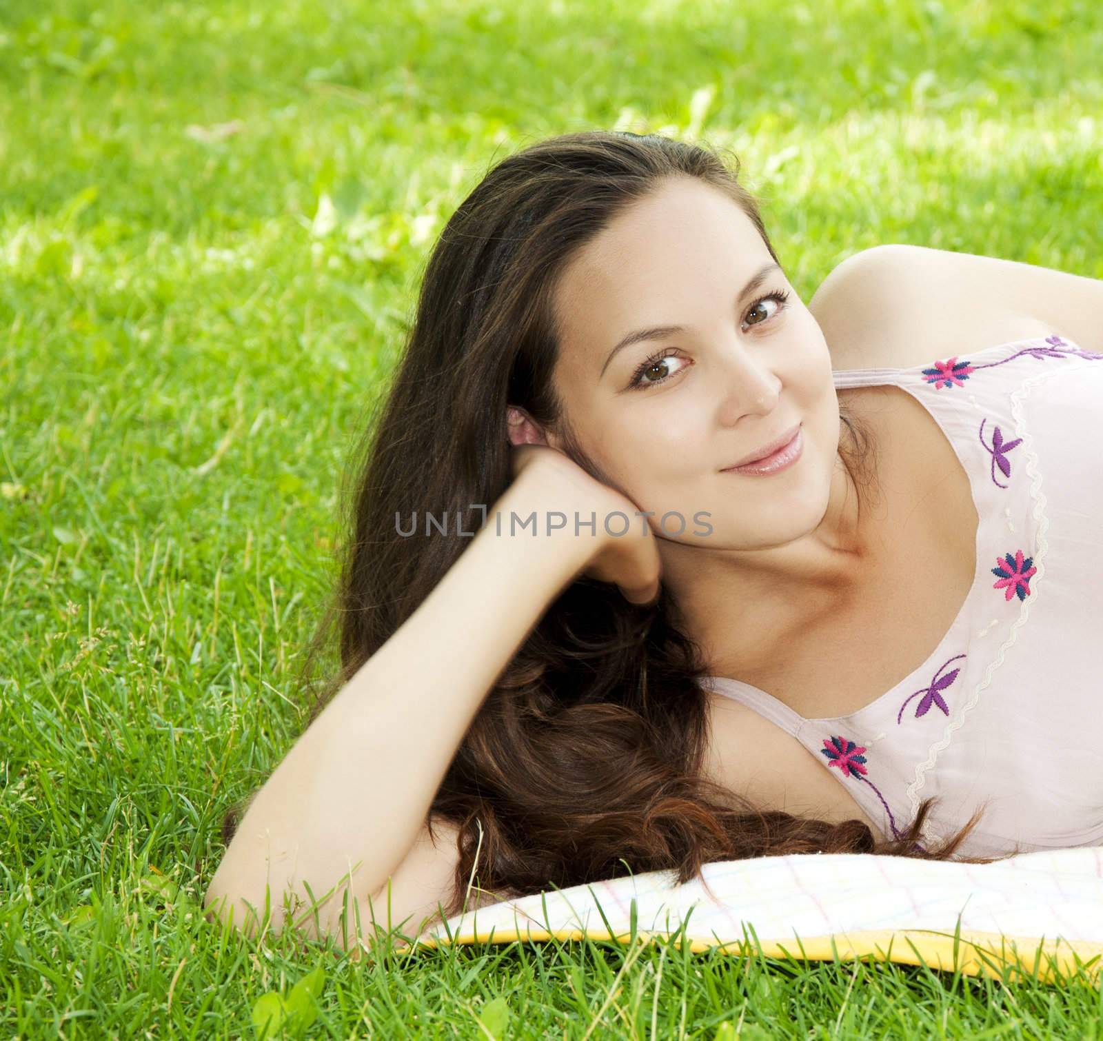 A very beautiful young woman lying down smiling in a field