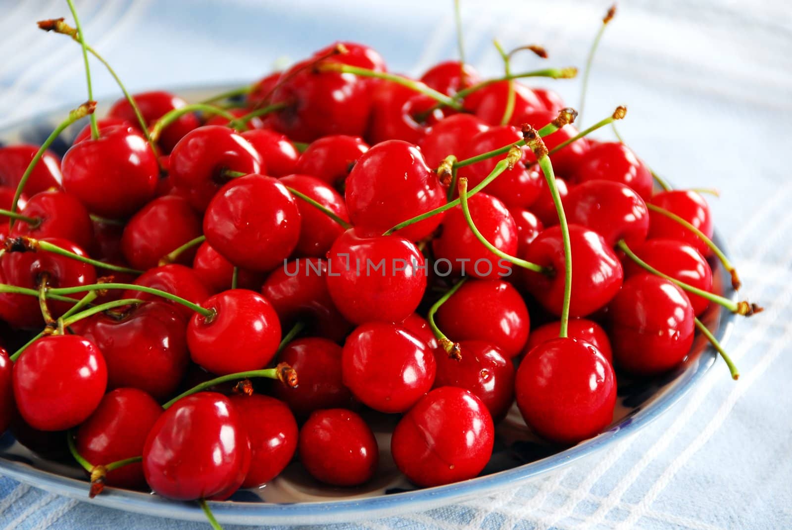 Heap of fresh appetizing red cherries on plate indoors