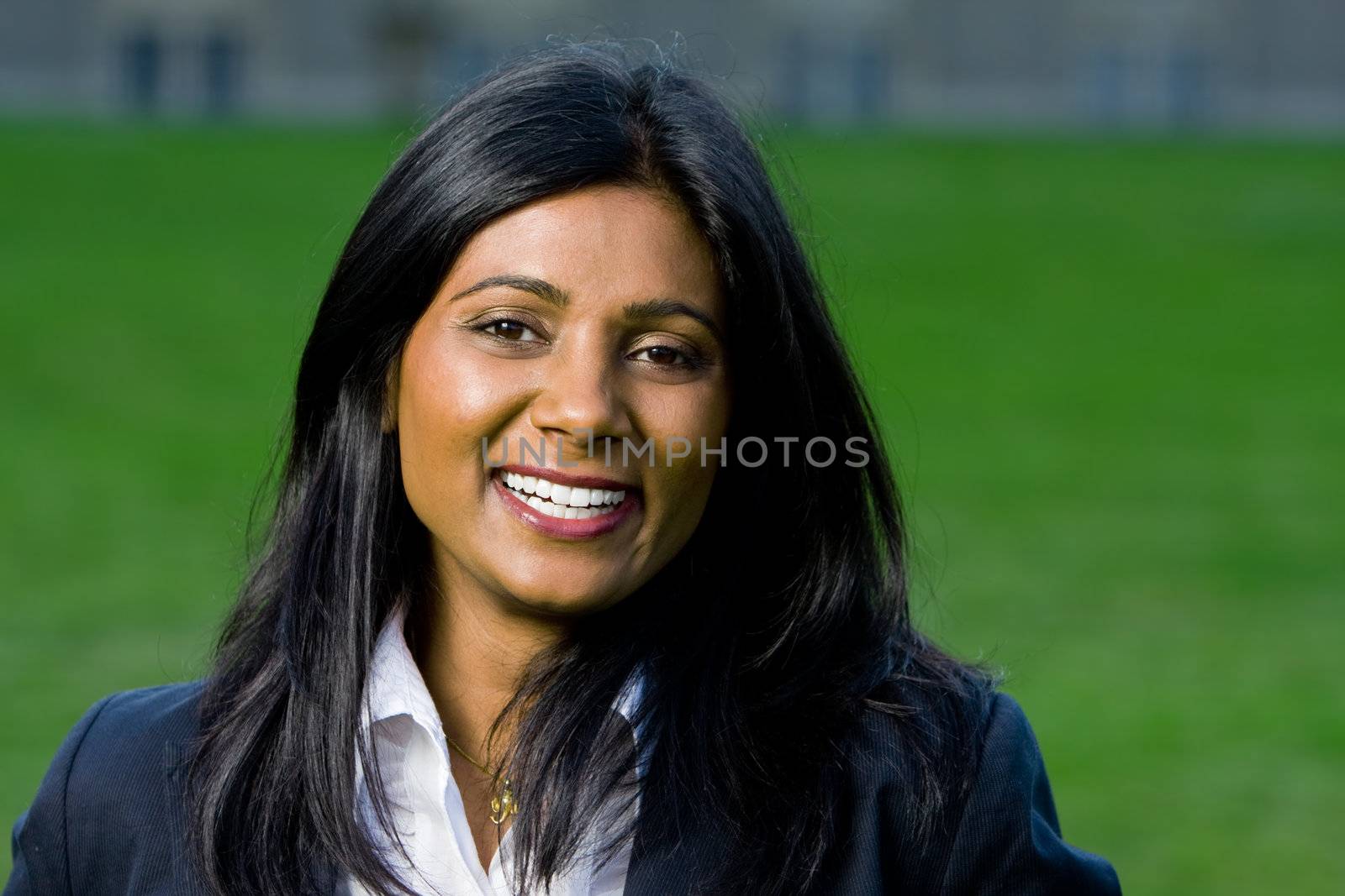 Beautiful indian girl smiling outdoors at the park with green grass