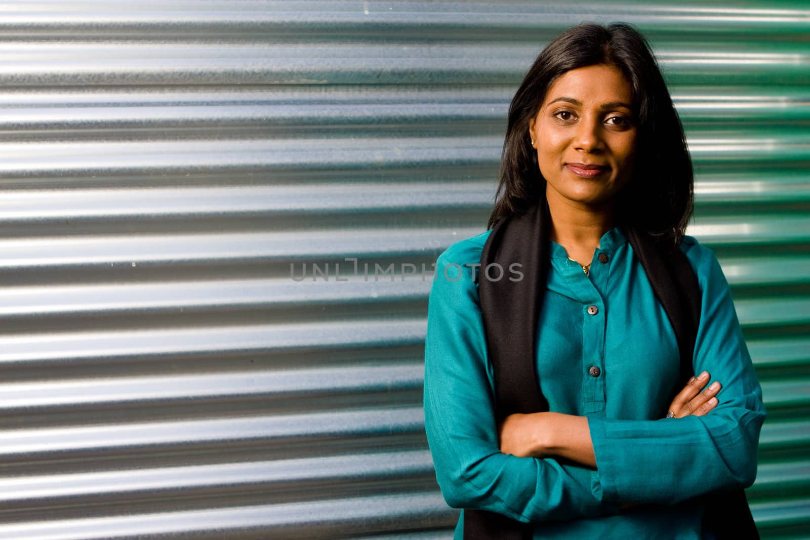 Pretty young indian girl dress in a green dress against a metallic background