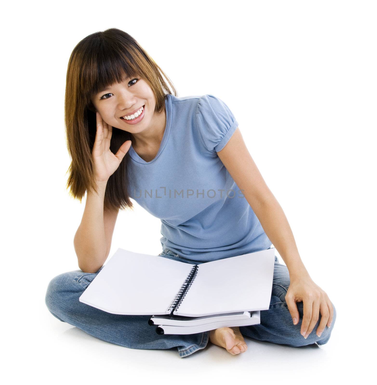 Asian student sitting on floor, blank book ready for text.