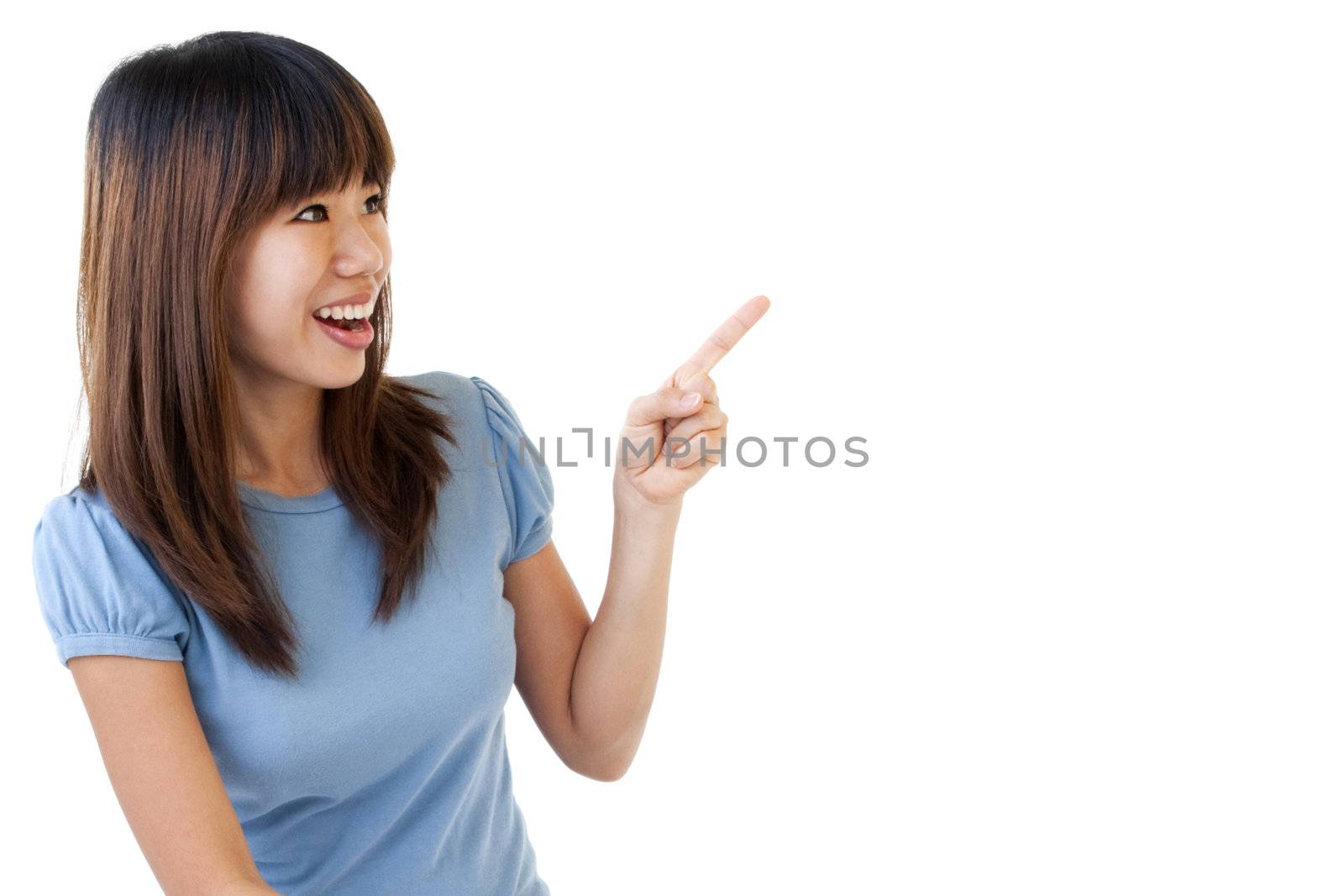 Asian student sitting on floor, pointing to empty space, ready for text.