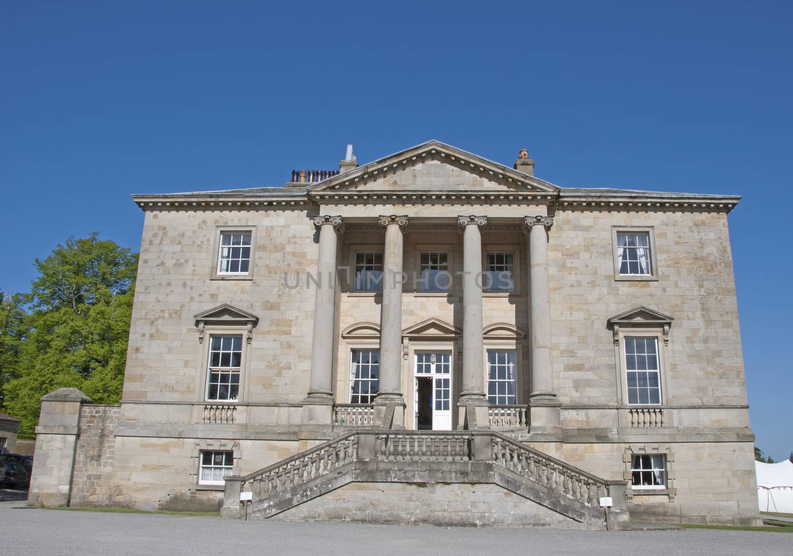An Eighteenth CenturyStately Home built in the Palladian Style with ionic pillars under a blue sky