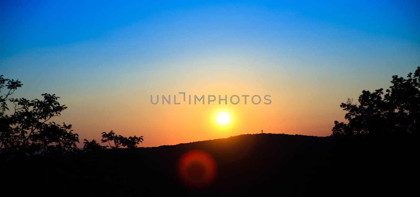 wounderful sunset with sun and siluet of trees and mountains by anobis