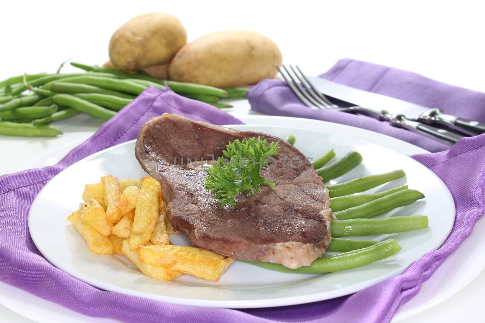 a slice of leg of lamb with green beans and french fries