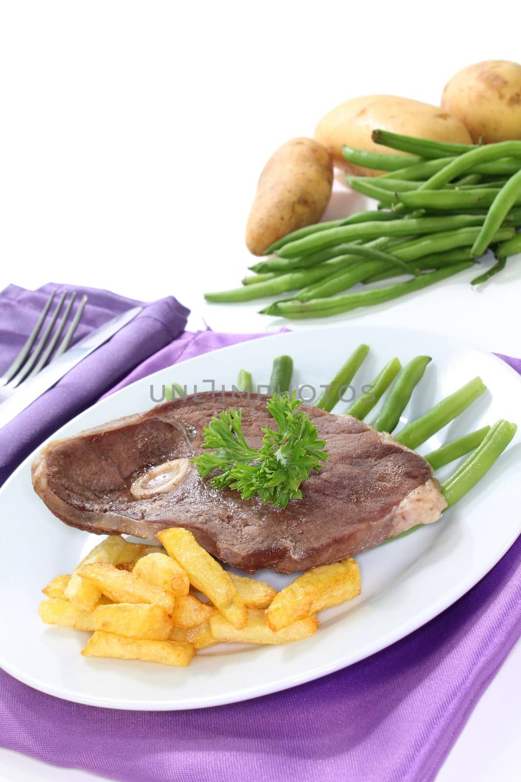 a slice of leg of lamb with green beans and french fries
