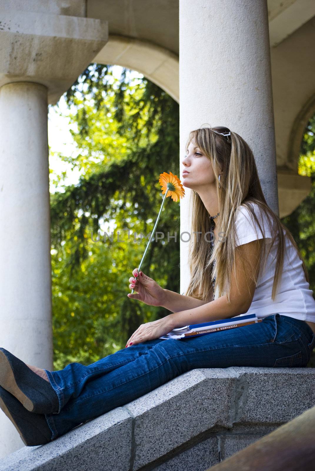 beautiful young woman with books and flower outdoor