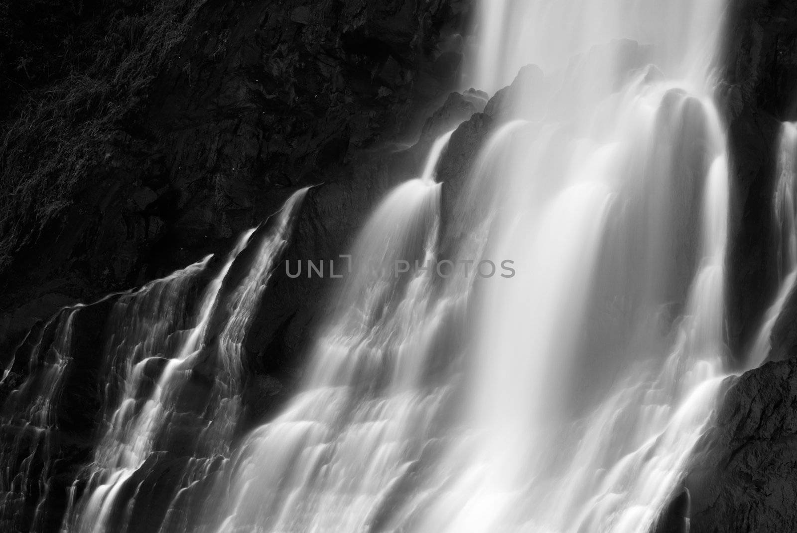 It is dramatic blurred view of waterfall flowing over rocks.
