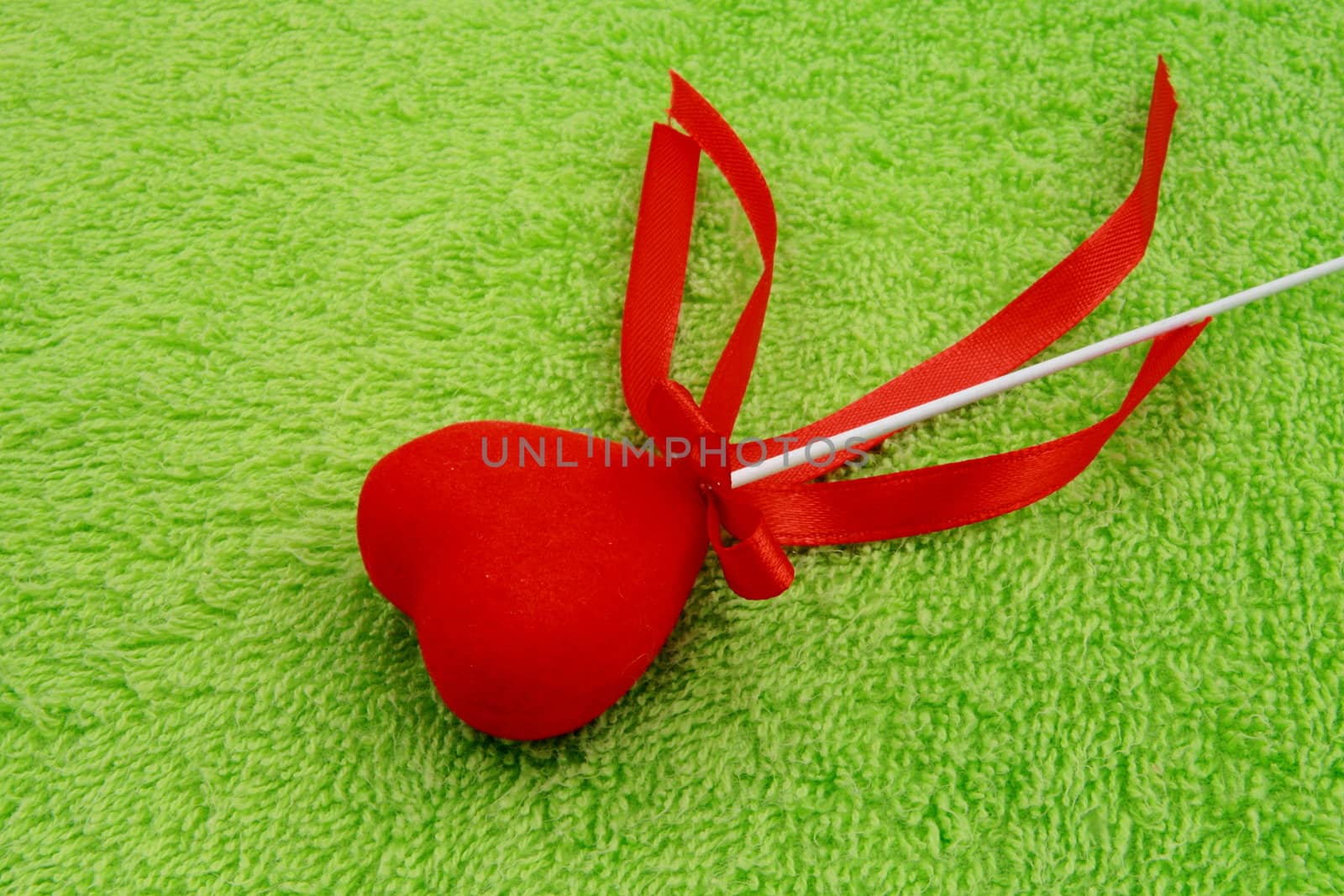 red heart with ribbons on green fabric