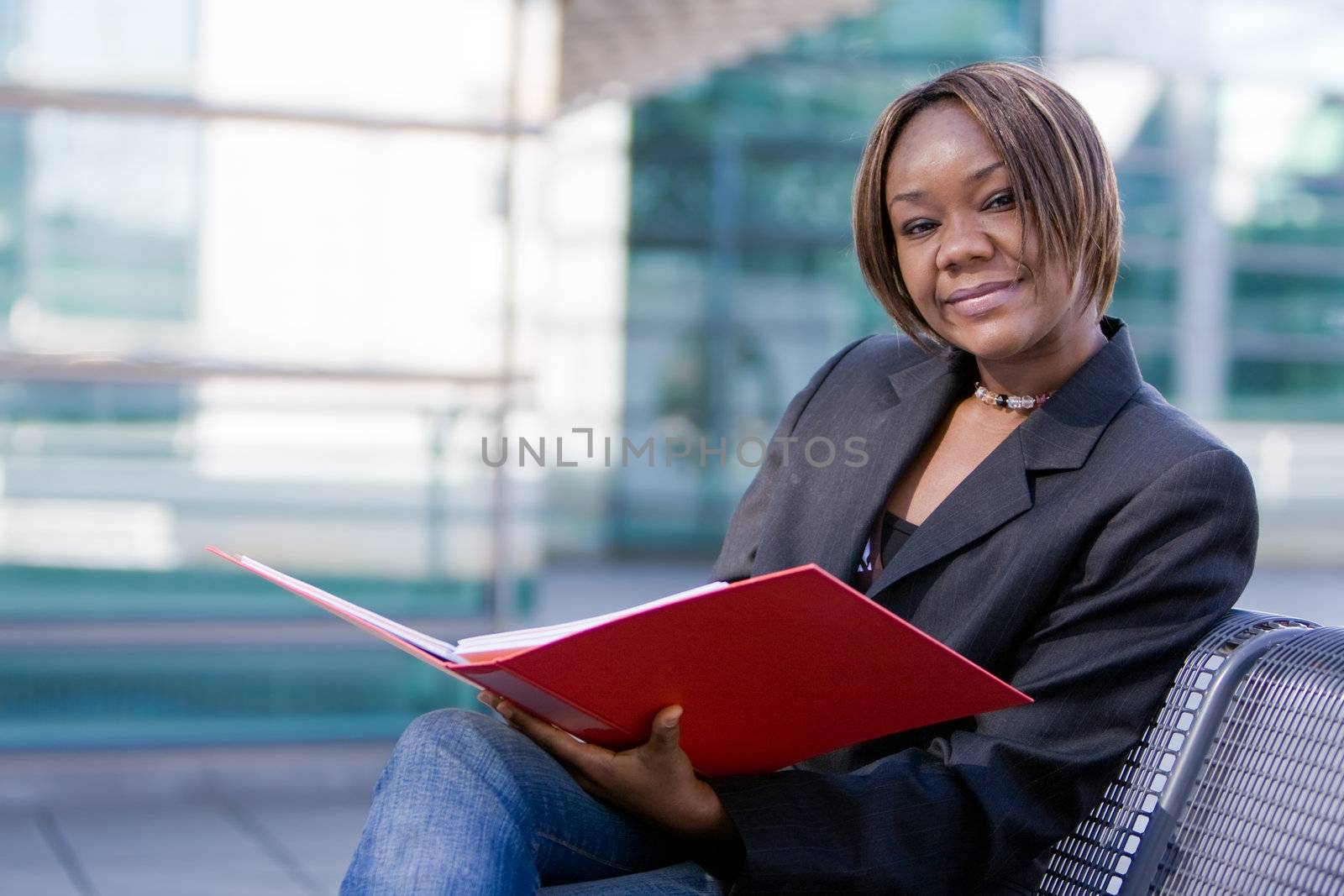 African american business woman reading documents in a folder in front of an office building