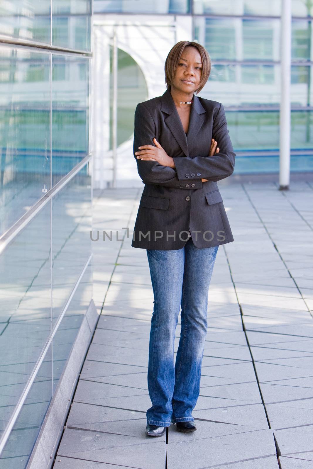 Black african american business woman posing in front of a modern office building with arms folded