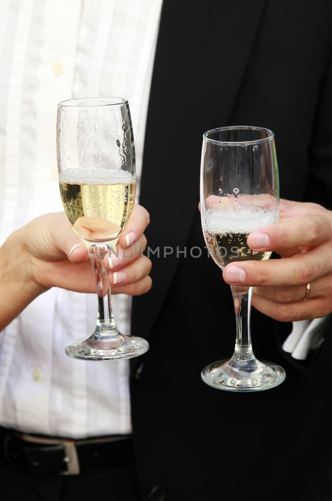 Glasses of champagne in a hand of the groom and bride