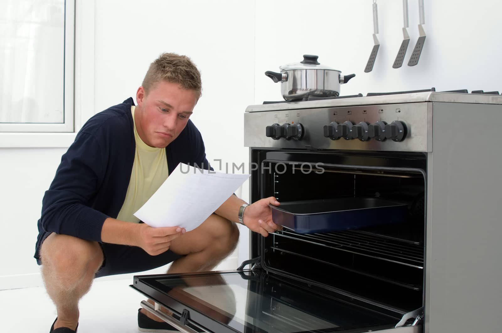 young man clueless in kitchen reading from recipe
