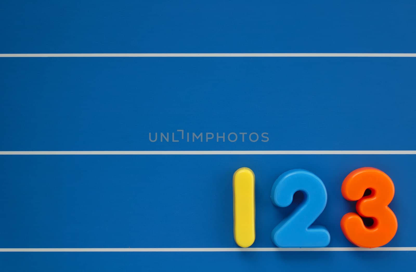 The numbers 1, 2 and 3 from a child's toy alphabet set, placed on a blue, lined background. Space for text elsewhere in the image.