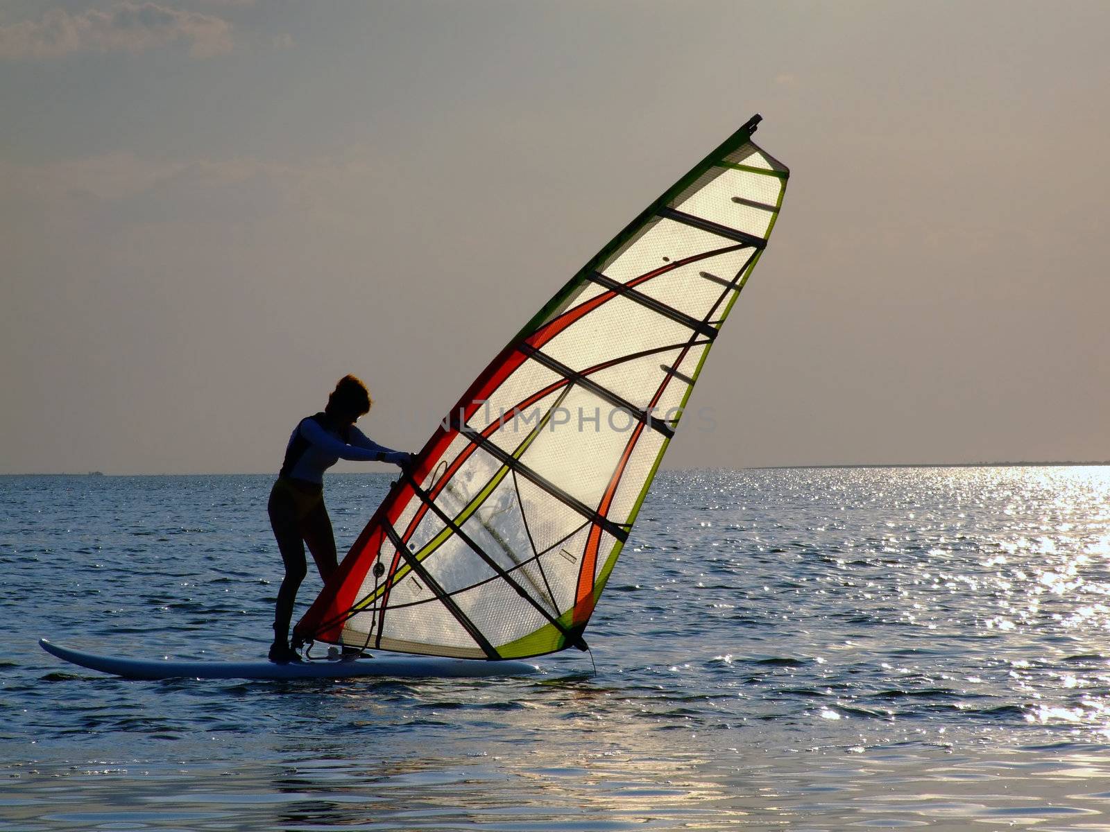 A women is learning windsurfing at the sunset 2