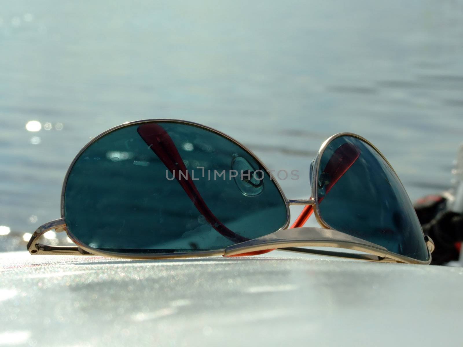 The sunglasses laying on a white surface on a background of water