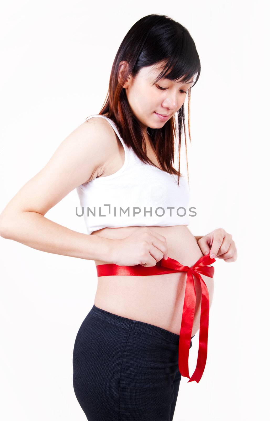 Young Asian pregnant women with red bow tied on her stomach.