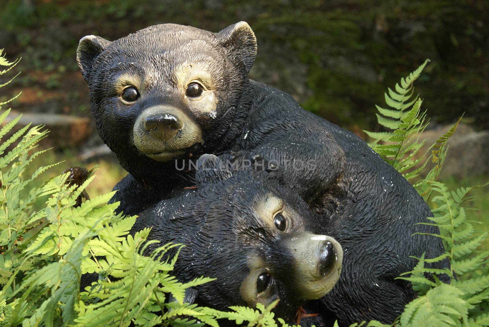 A bear cub statue in amongst some foliage.