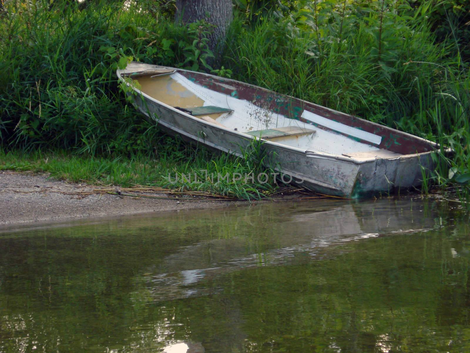 An old boat sits on the shore of a secluded launch.