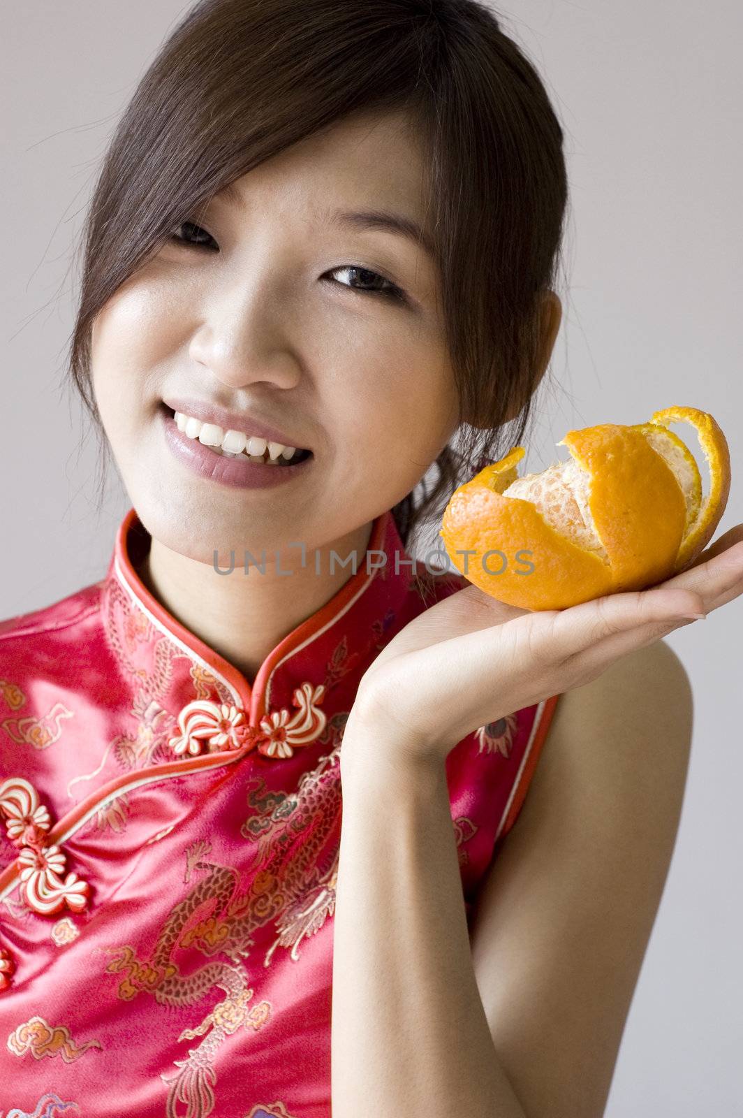 Pretty asian with cheongsam wear holding a mandarin orange 