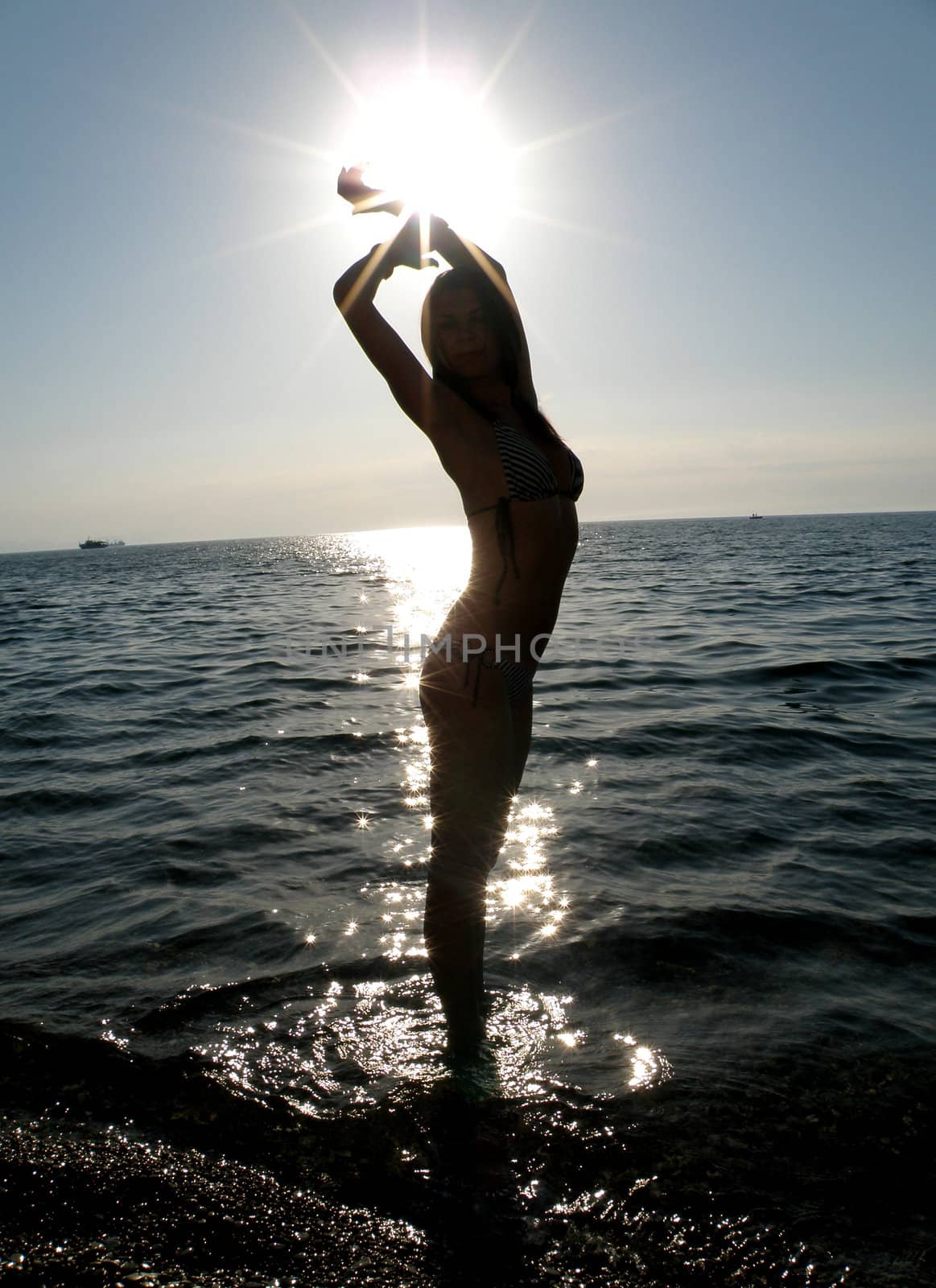 The fine young girl in sun beams laps in a sea wave      