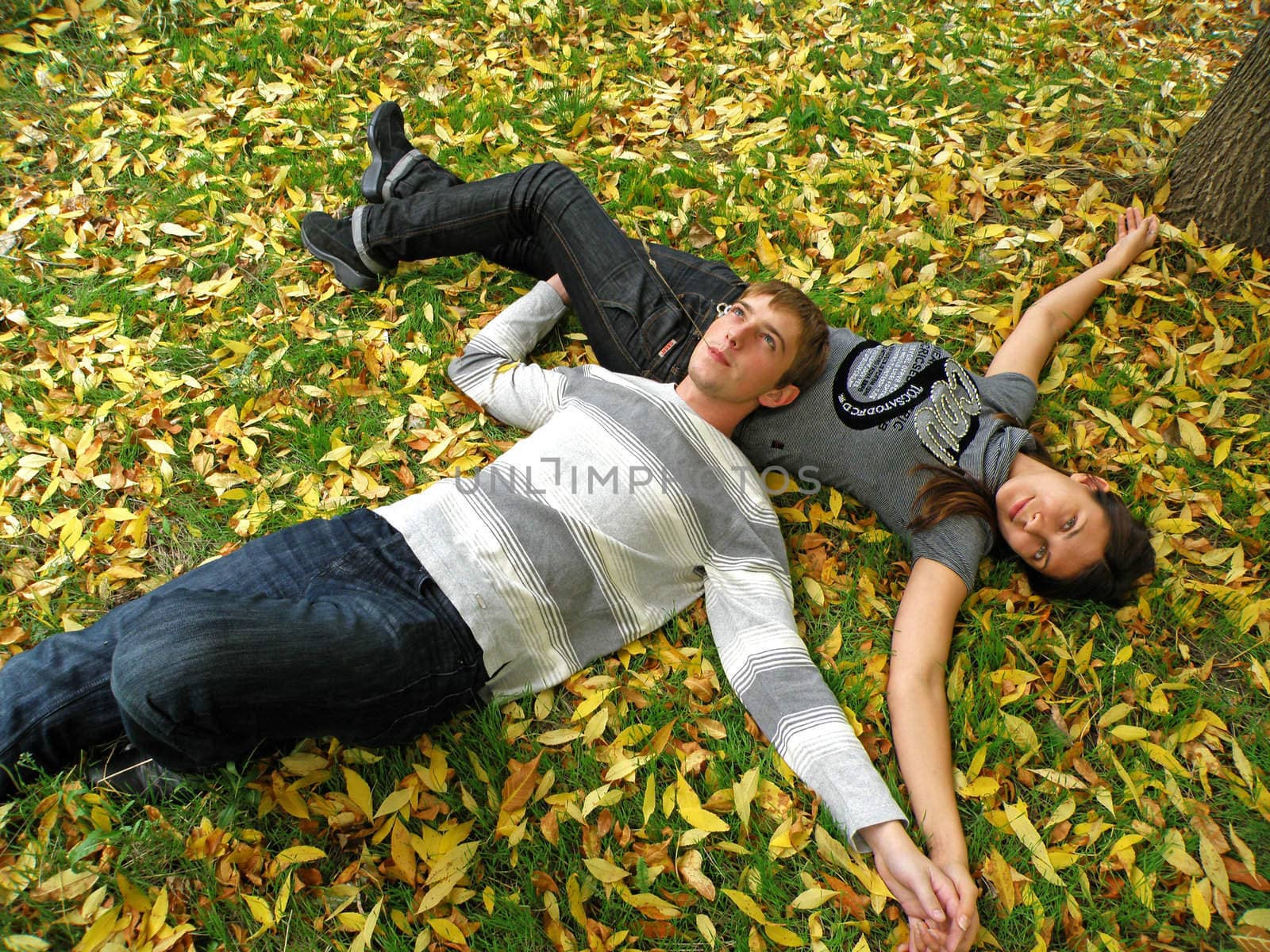 The young pair costs on a footpath in autumn park