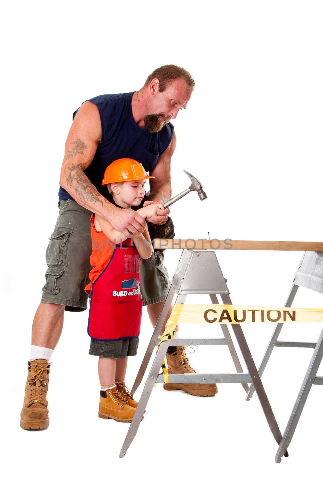 Caucasian father teaching his cute son how to hold a hammer and hit a nail into a wooden plank, isolated.