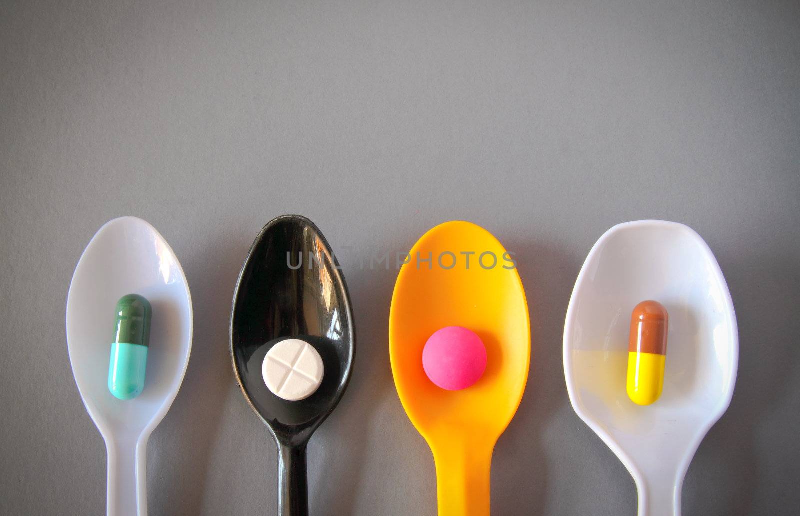 four spoons with different pills with copy space