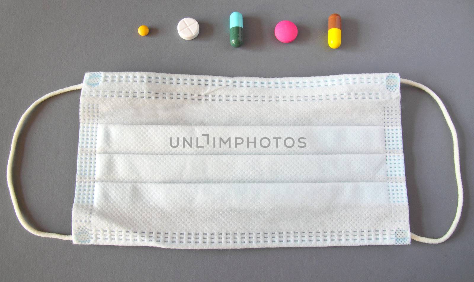 Set of various medical pills and mask on grey background
