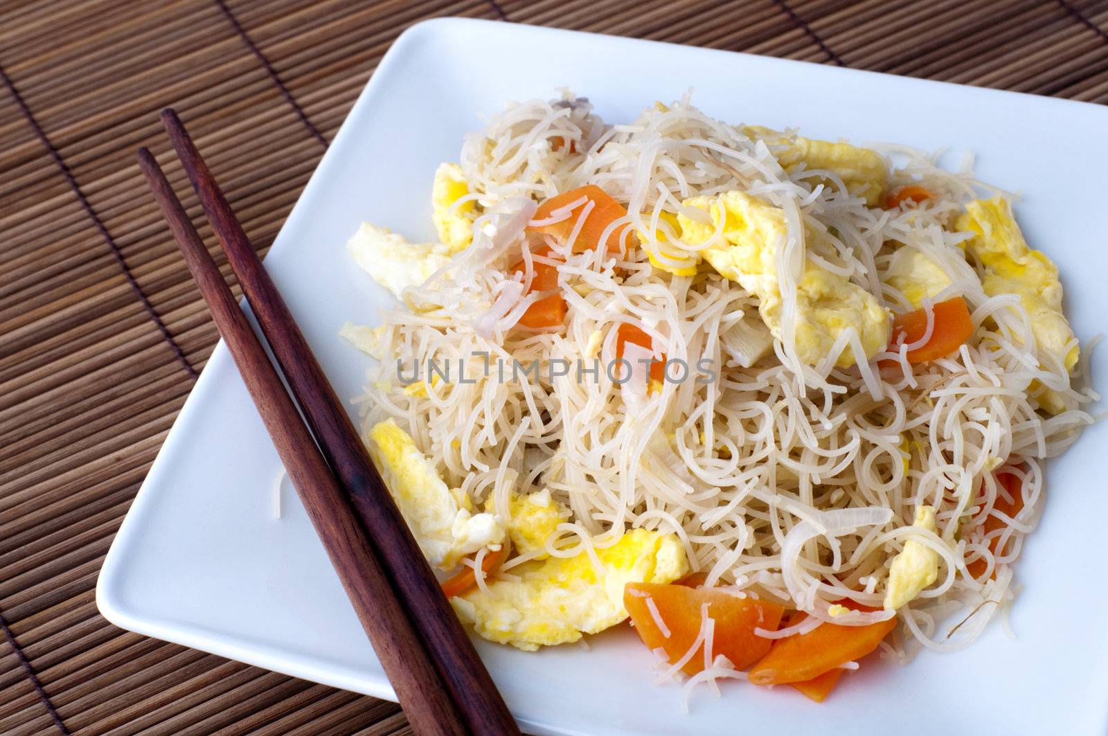 Asian fried rice vermicelli with eggs and carrot. Serve with chopsticks.