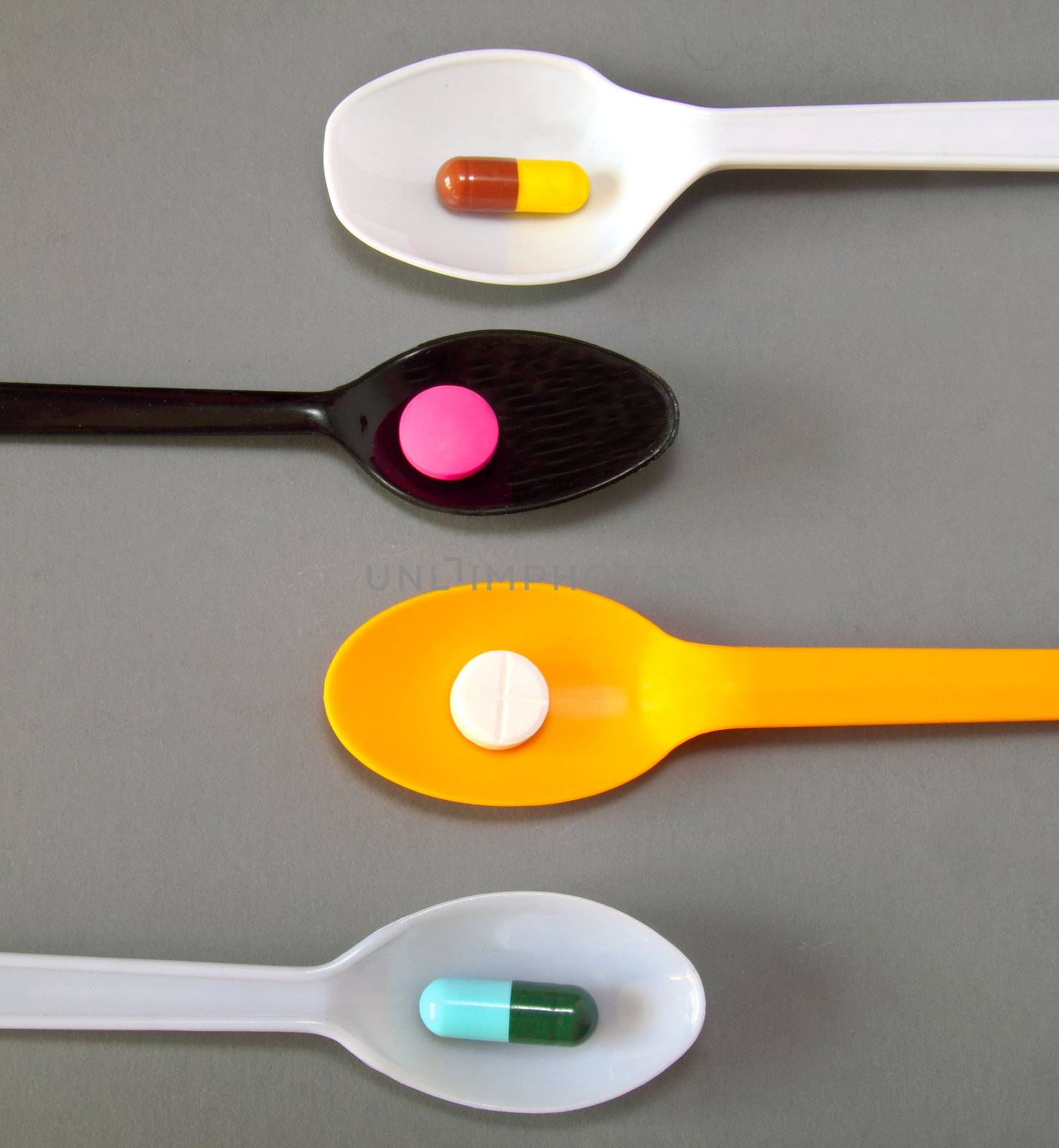 four spoons with different pills by nuchylee