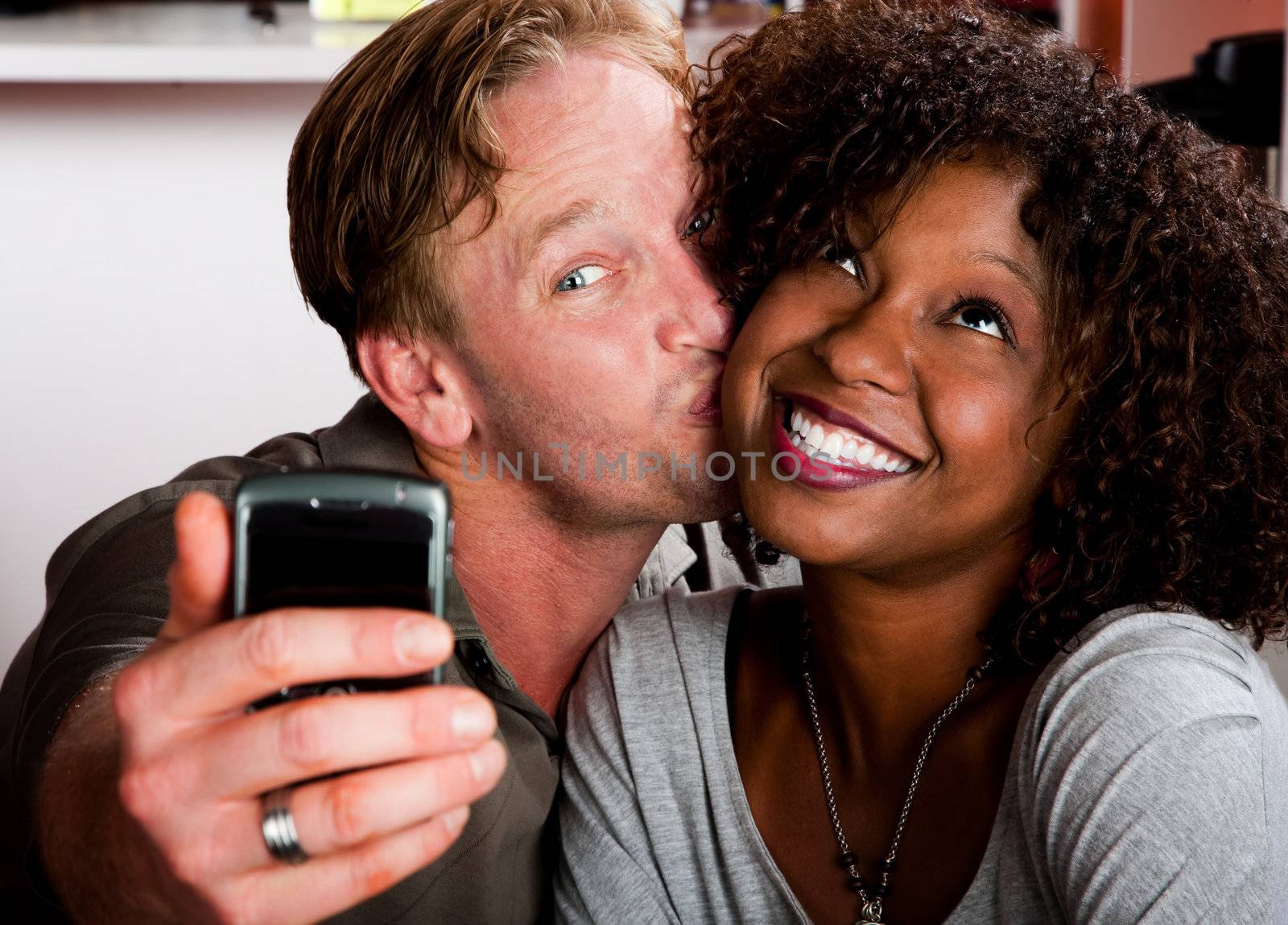 Mixed race couple in coffee house with taking picture cell phone by Creatista