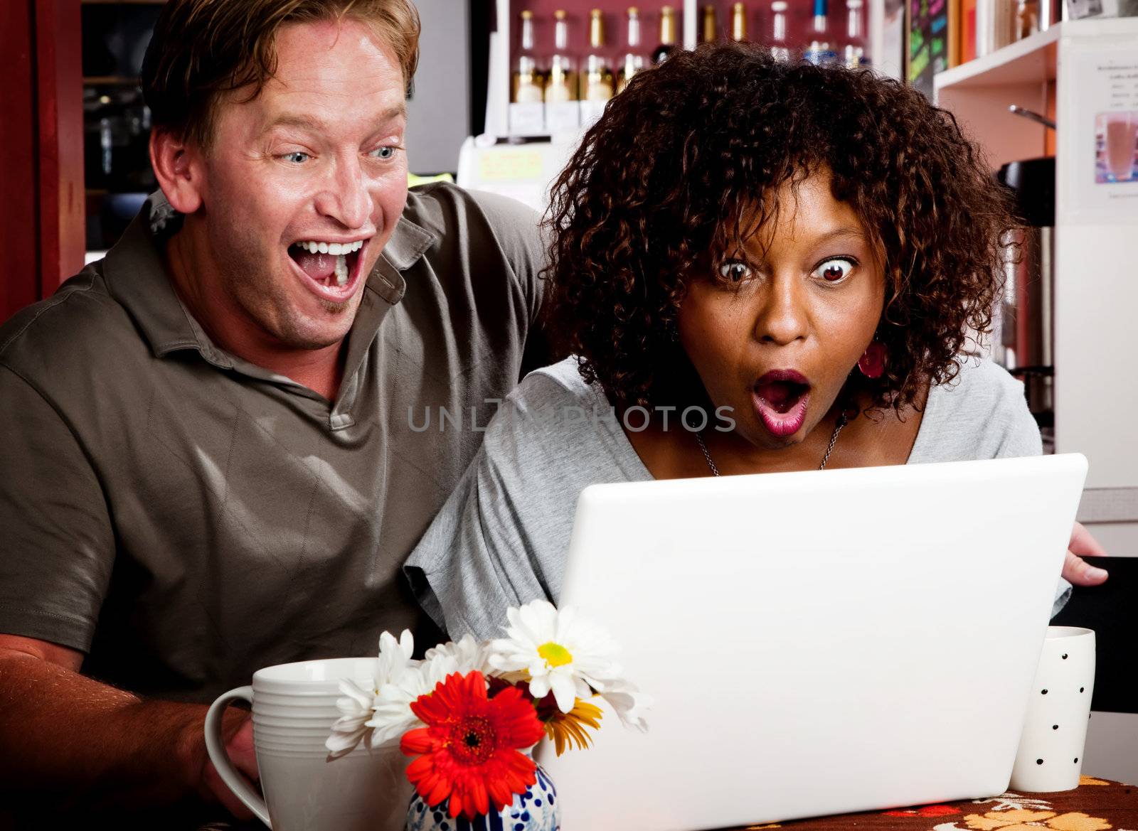 Caucasian man and African American woman in coffee house with laptop computer
