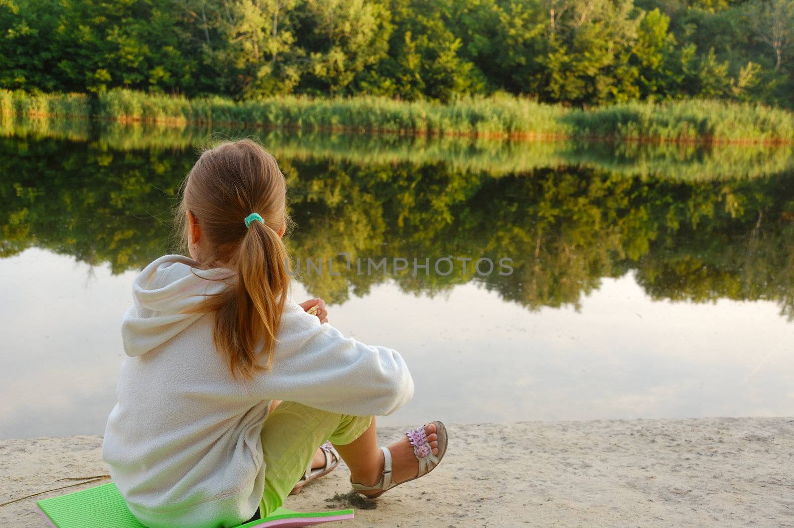 little girl relaxing on a river beach on an early summer morning