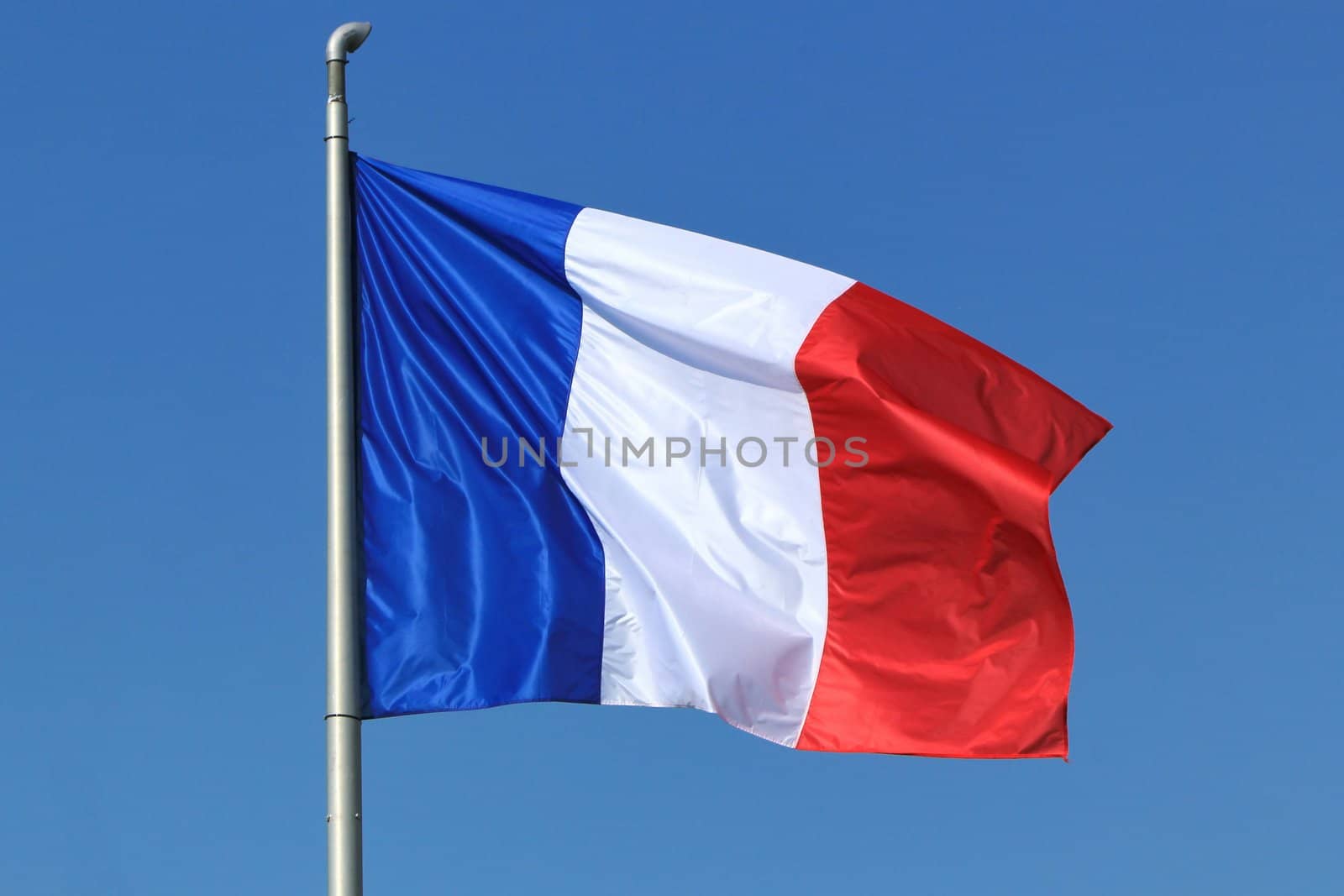 Blue, white and red french flag floating in the wind in a deep blue sky background