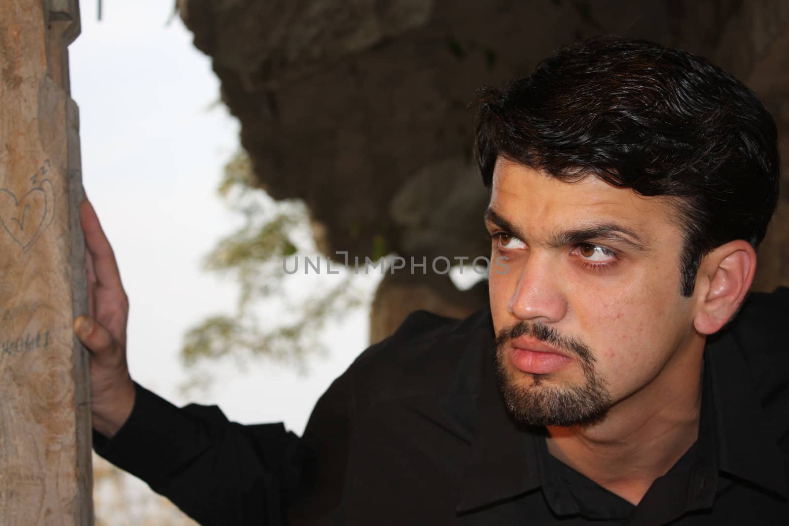 A portrait of a daydreaming young Indian man.