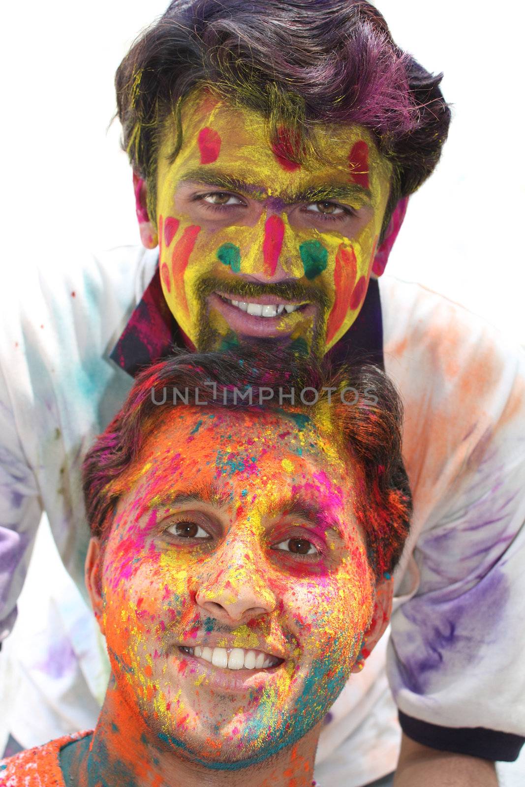 Two young guys with their faces tradiitionally painted in colorful powders, on the occasion of holi festival in India.
