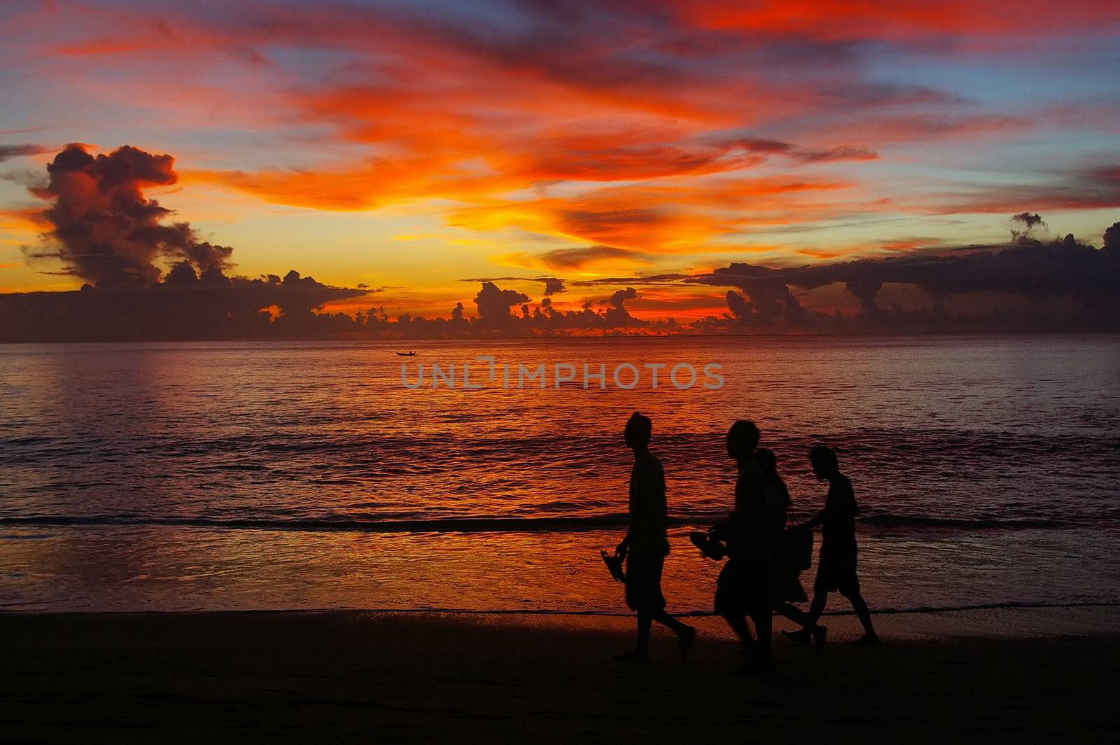 Young men walking on the beach at sunset, Dreamland, Bali, Indonesia.