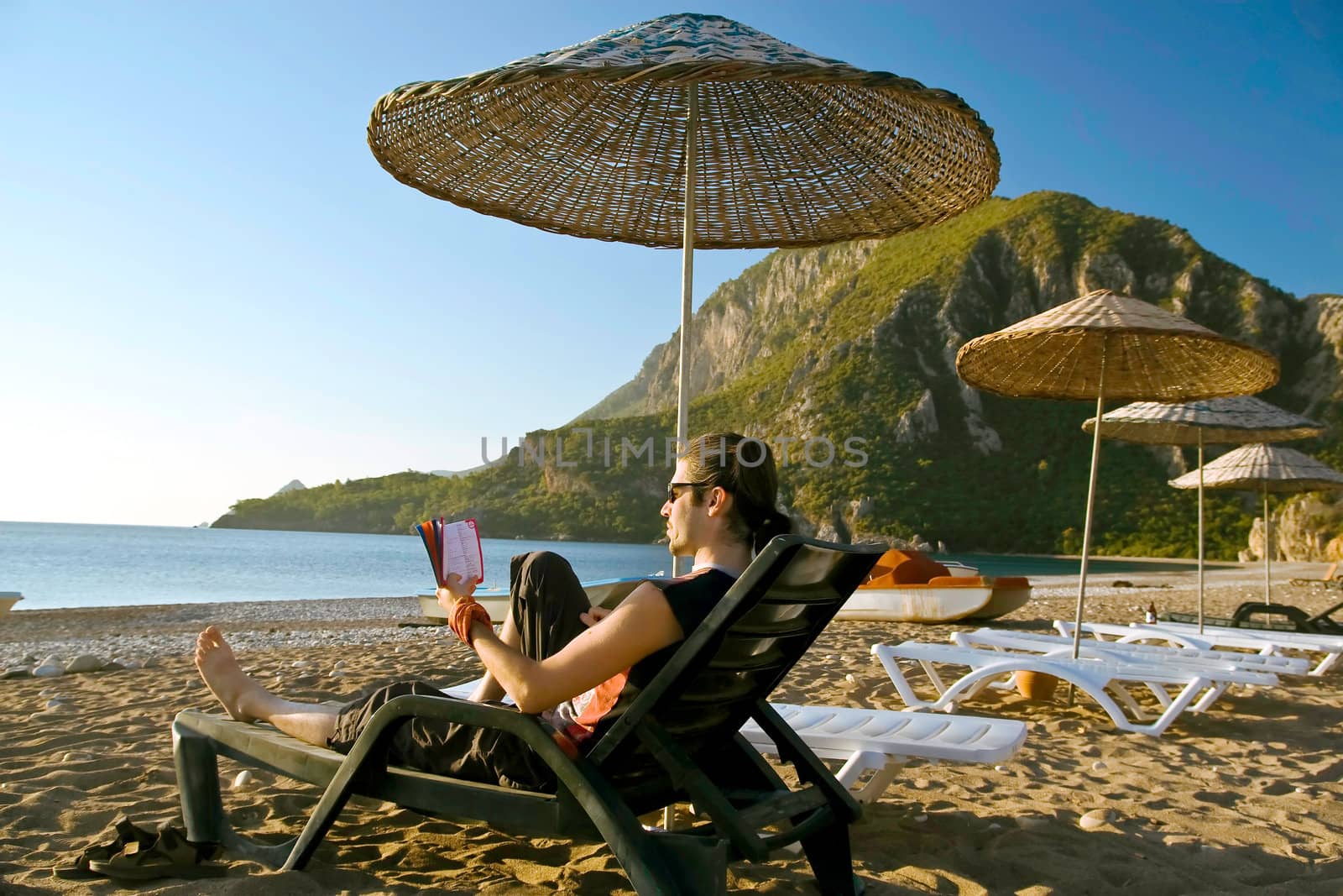 Man reading a book on beach by Keetten_Predators