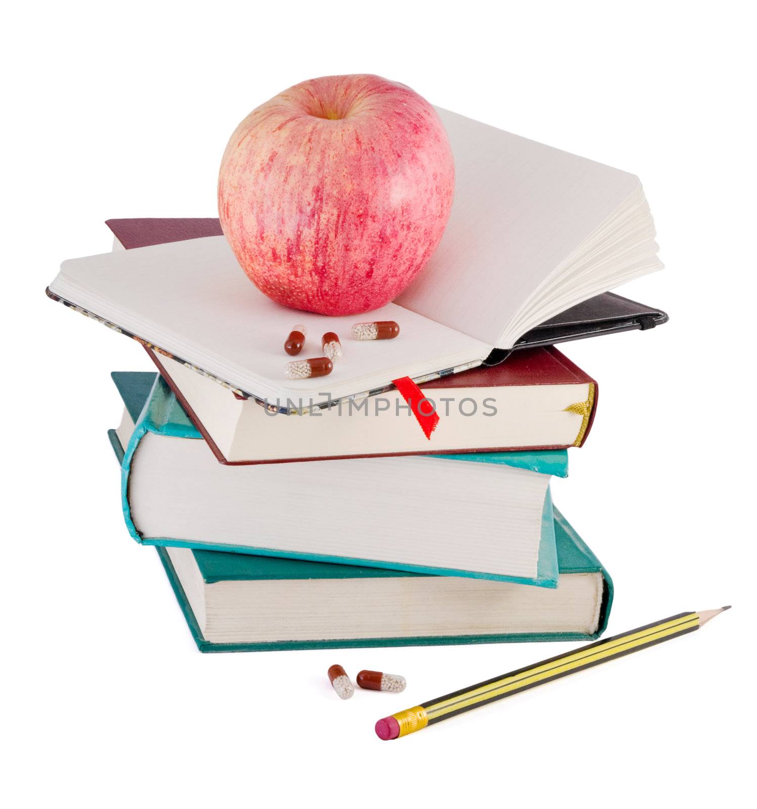 Pills and red apple on textbook pile as metaphor of efective learning