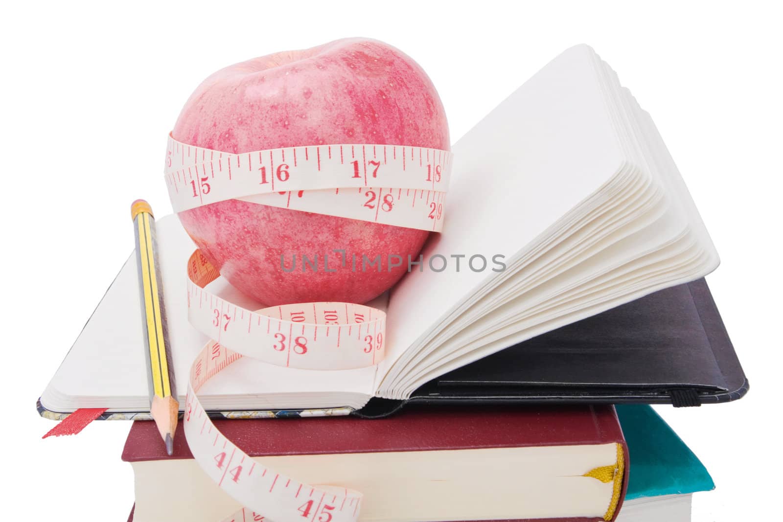 Big ripe red apple with white measure tape around it on pile of books as metaphor of healthy eating and diet