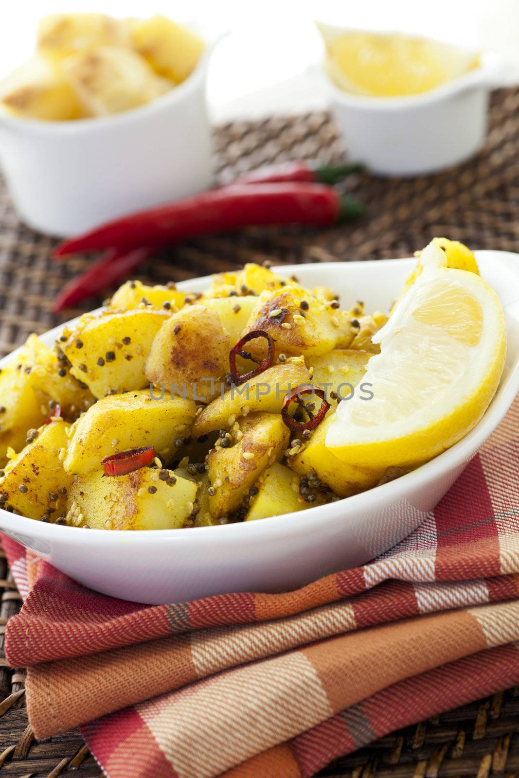 Spicy Potatoes with mustard seeds, sesame seeds, chili peppers and other spices, served with a slice of lemon.