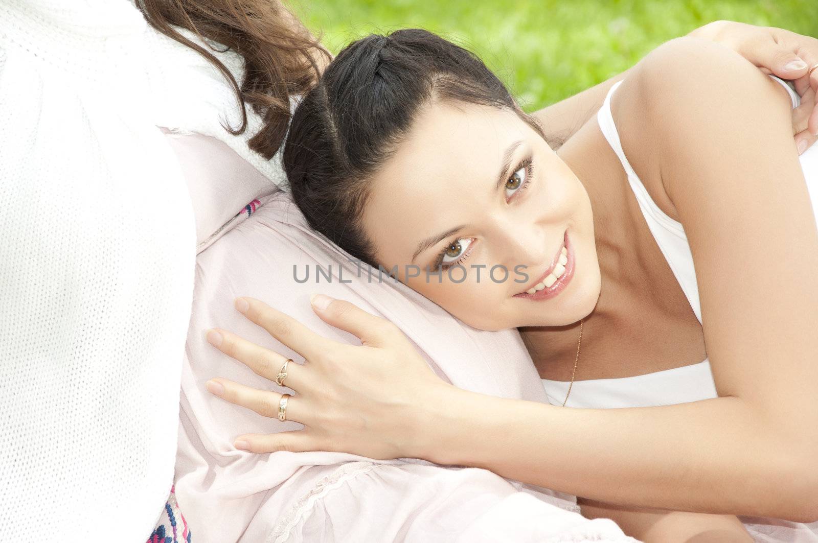 woman huging pregnant stomach, green grass background