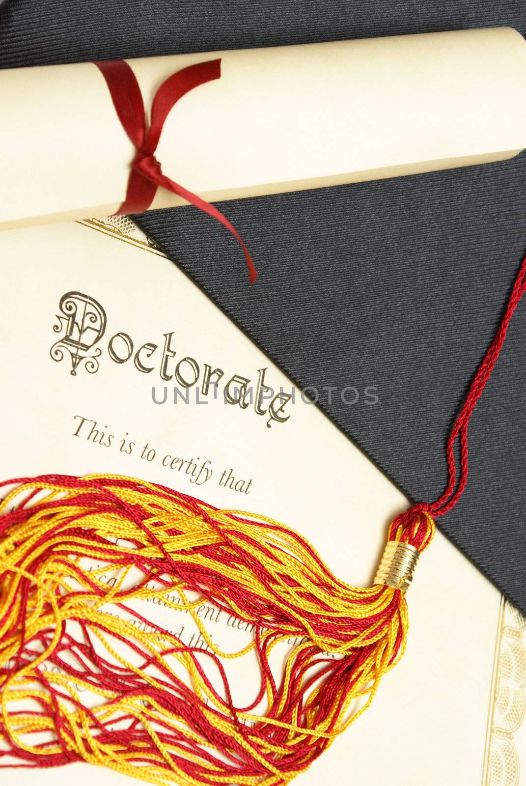 A closeup shot of a doctorate and diploma scroll with the tassels of a mortar board.