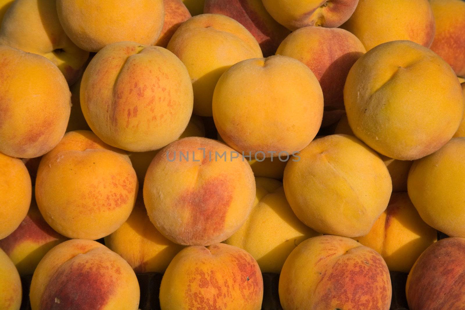 A background of tiled fresh yellow peaches.