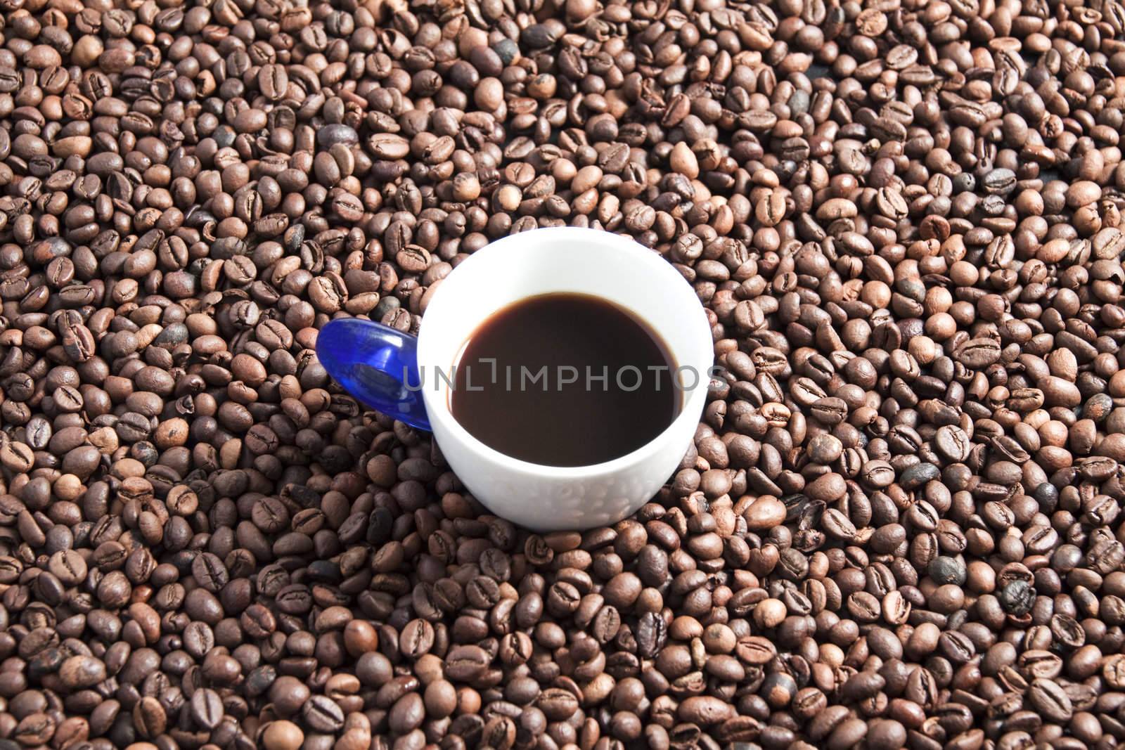 A cup full of coffee surrounded by other coffee beans
