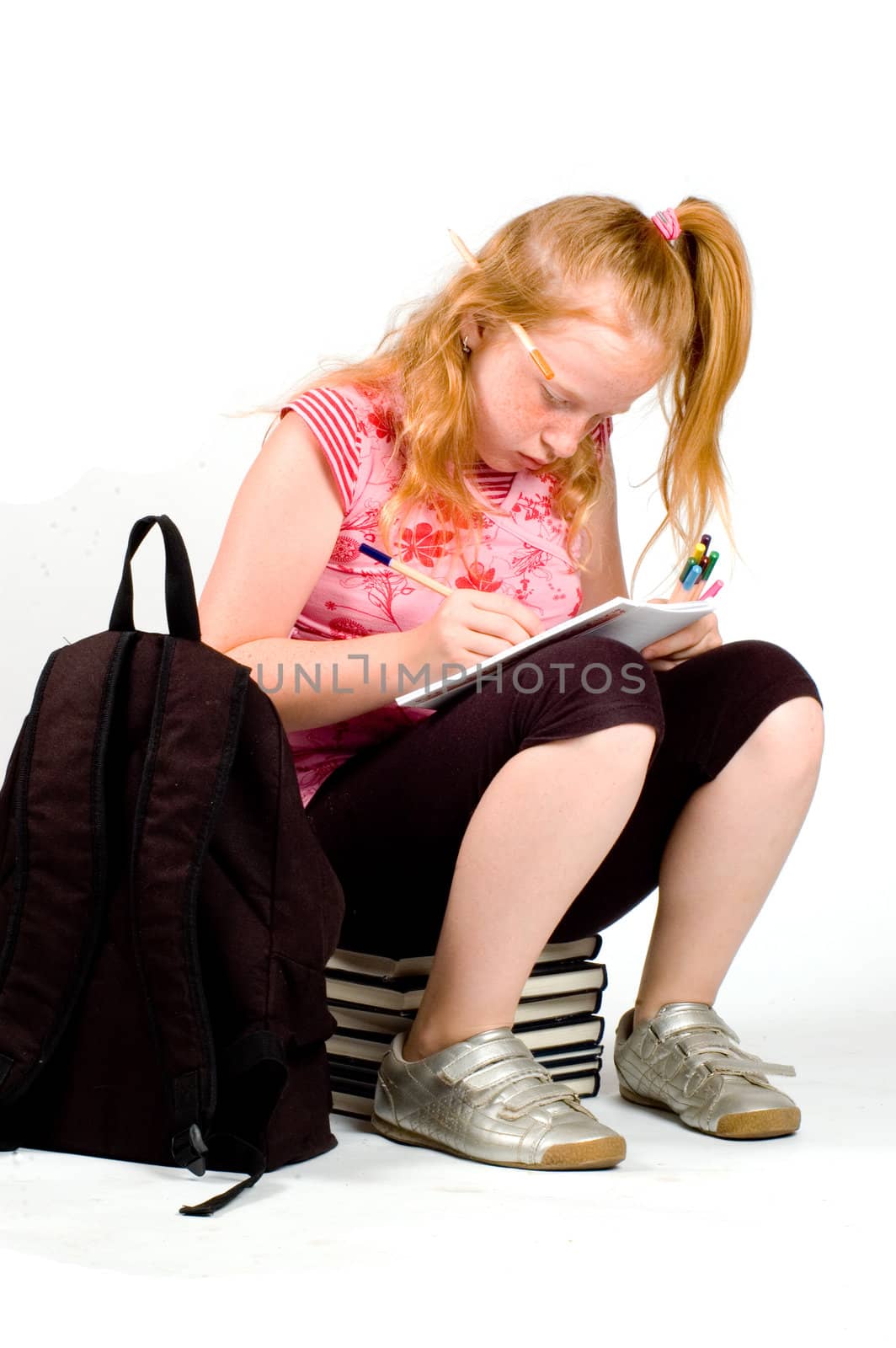 schoolgirl sitting on a stack of books making homework by ladyminnie