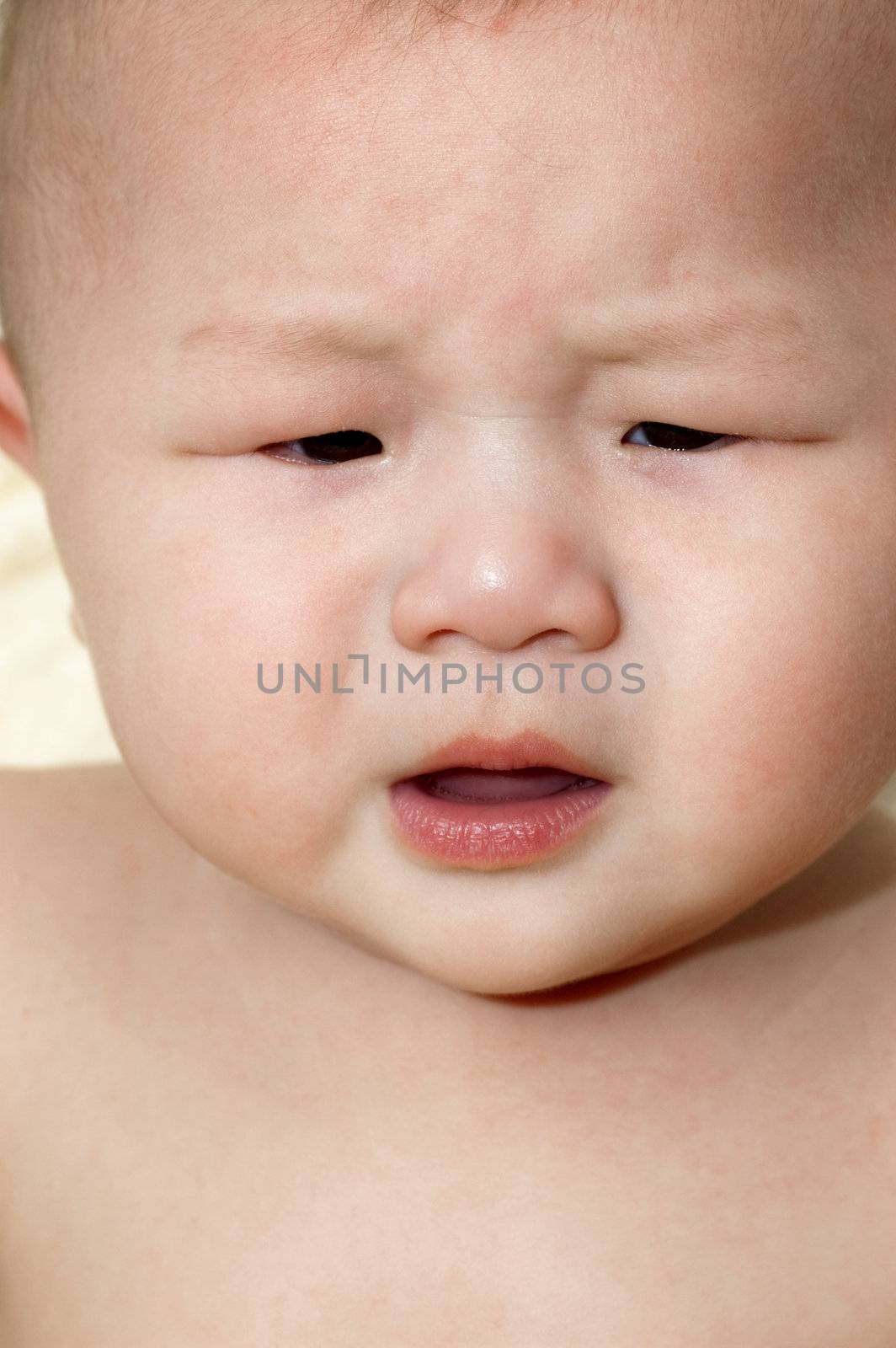An upset Asian baby boy is crying.